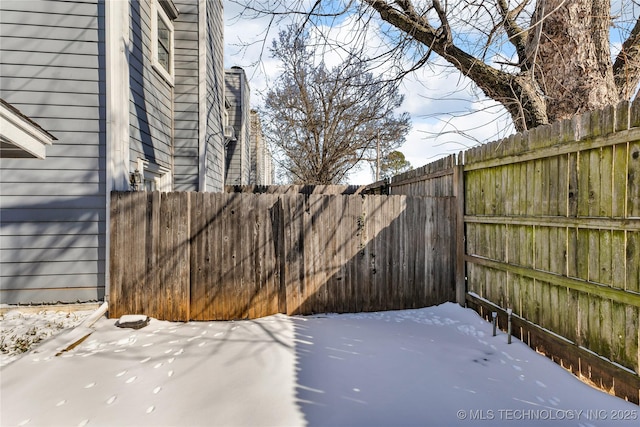 snow covered patio featuring a fenced backyard