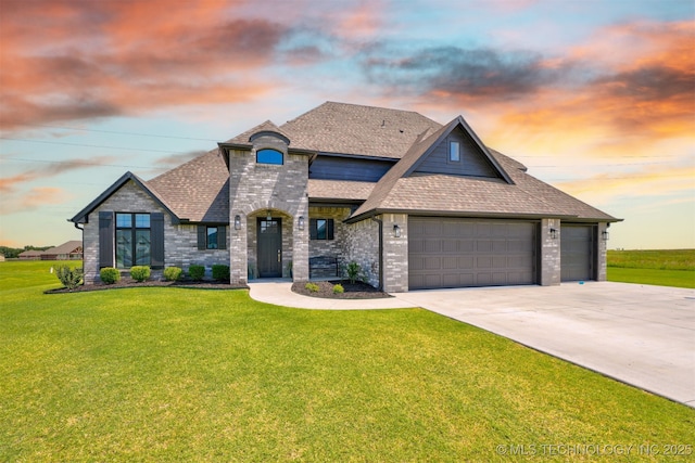 french country style house featuring brick siding, a shingled roof, concrete driveway, and a yard