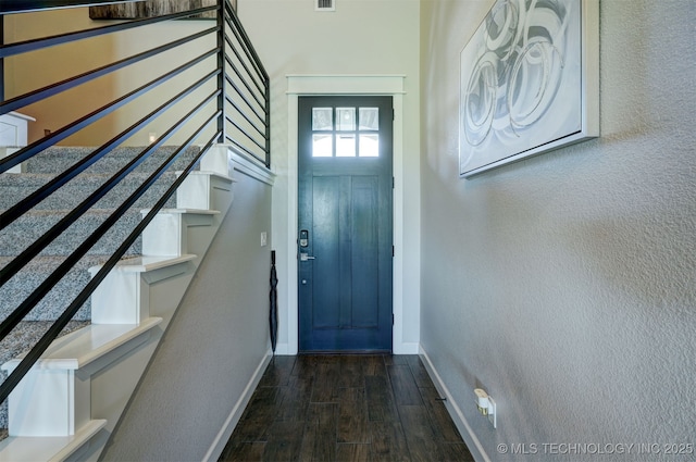 doorway with dark wood-style floors, visible vents, stairway, and baseboards