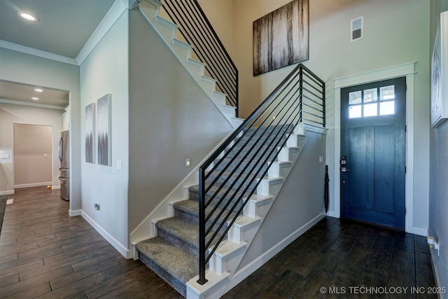 foyer with visible vents, baseboards, ornamental molding, and wood finish floors