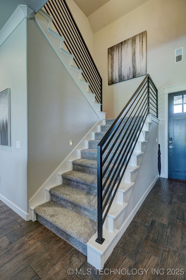 staircase with wood finished floors, visible vents, and baseboards