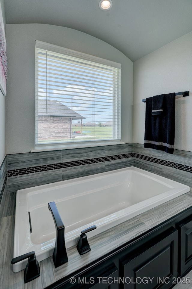 full bath featuring a garden tub and vaulted ceiling