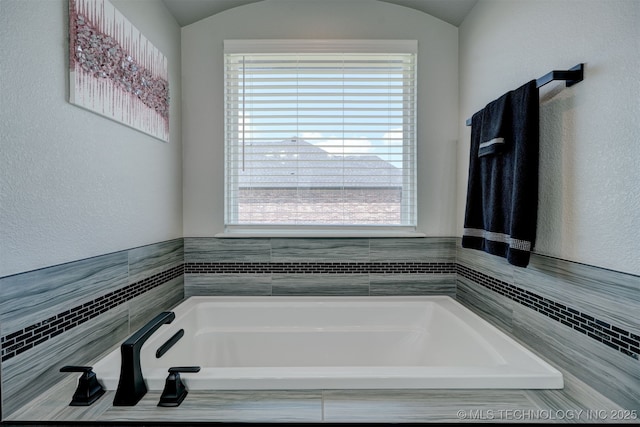 bathroom with lofted ceiling and a bath