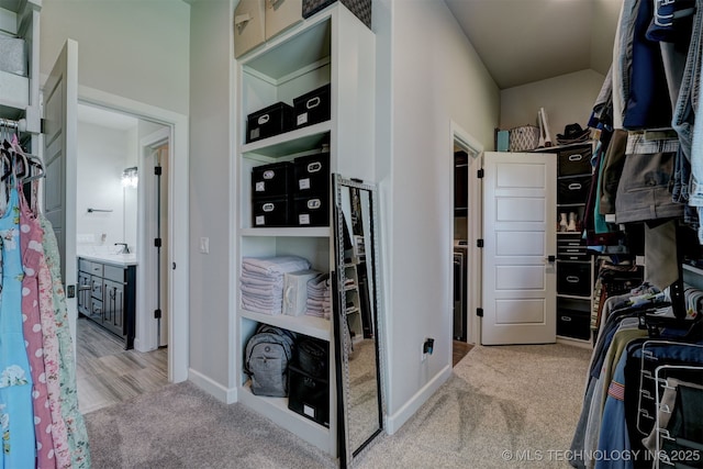 spacious closet featuring a sink and light colored carpet