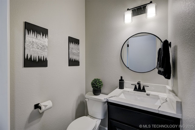 bathroom featuring a textured wall, vanity, and toilet