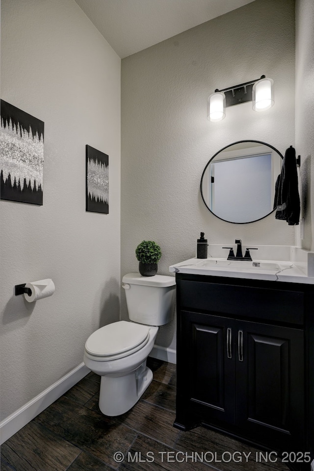 bathroom with vanity, wood finished floors, toilet, and baseboards