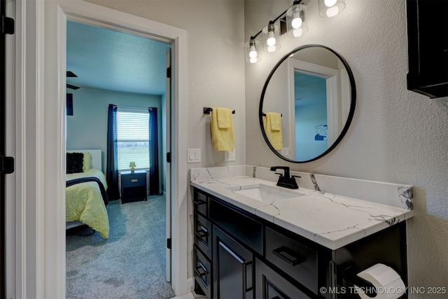 bathroom featuring a textured wall, connected bathroom, and vanity