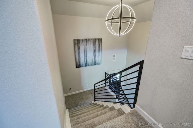 stairway with carpet flooring, a textured wall, baseboards, and an inviting chandelier