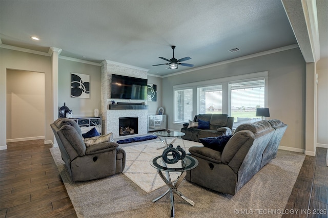 living area featuring a stone fireplace, dark wood-type flooring, visible vents, and baseboards