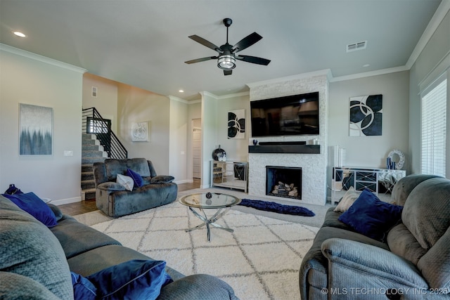 living area with visible vents, crown molding, a fireplace, and stairs