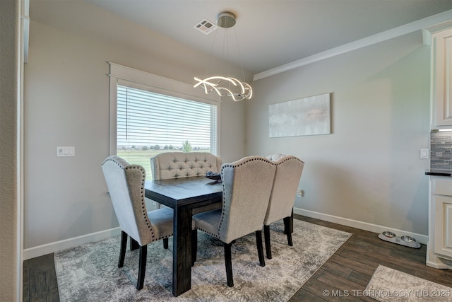 dining space with baseboards, visible vents, dark wood-style floors, crown molding, and a chandelier