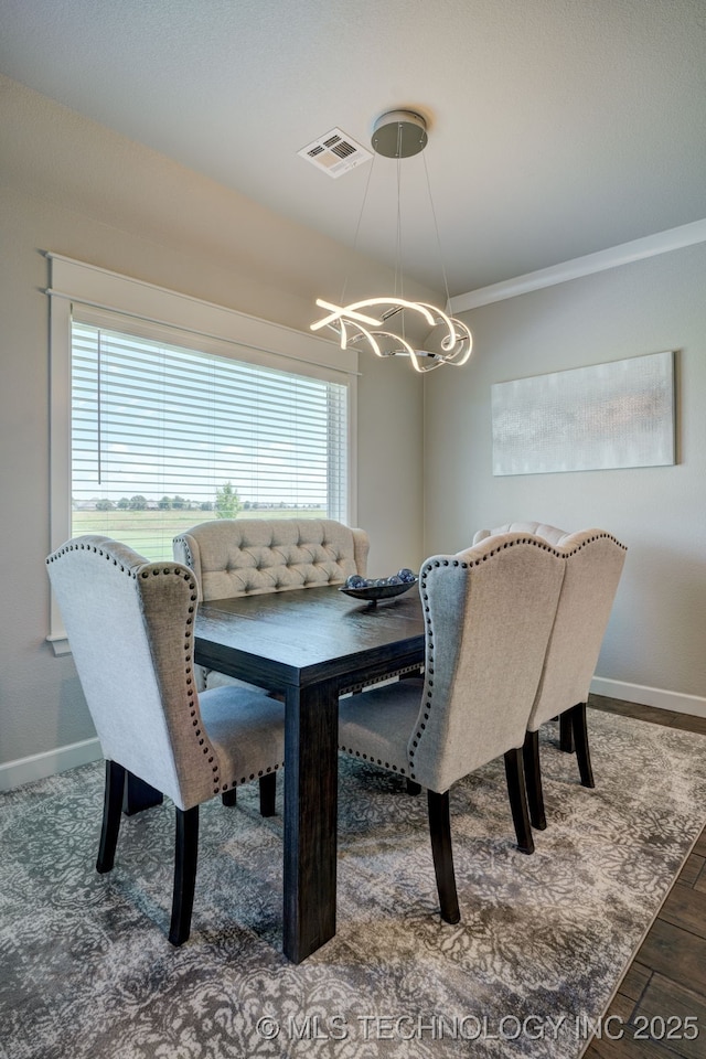 dining room with baseboards, crown molding, visible vents, and an inviting chandelier