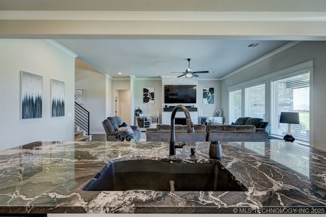 kitchen with a sink, visible vents, open floor plan, marble finish floor, and ornamental molding