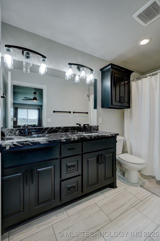 bathroom featuring double vanity, visible vents, toilet, and a sink