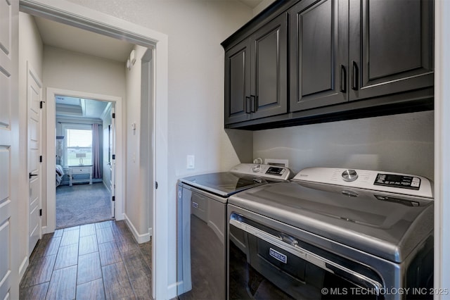 laundry room featuring dark wood-type flooring, washer and clothes dryer, cabinet space, and baseboards