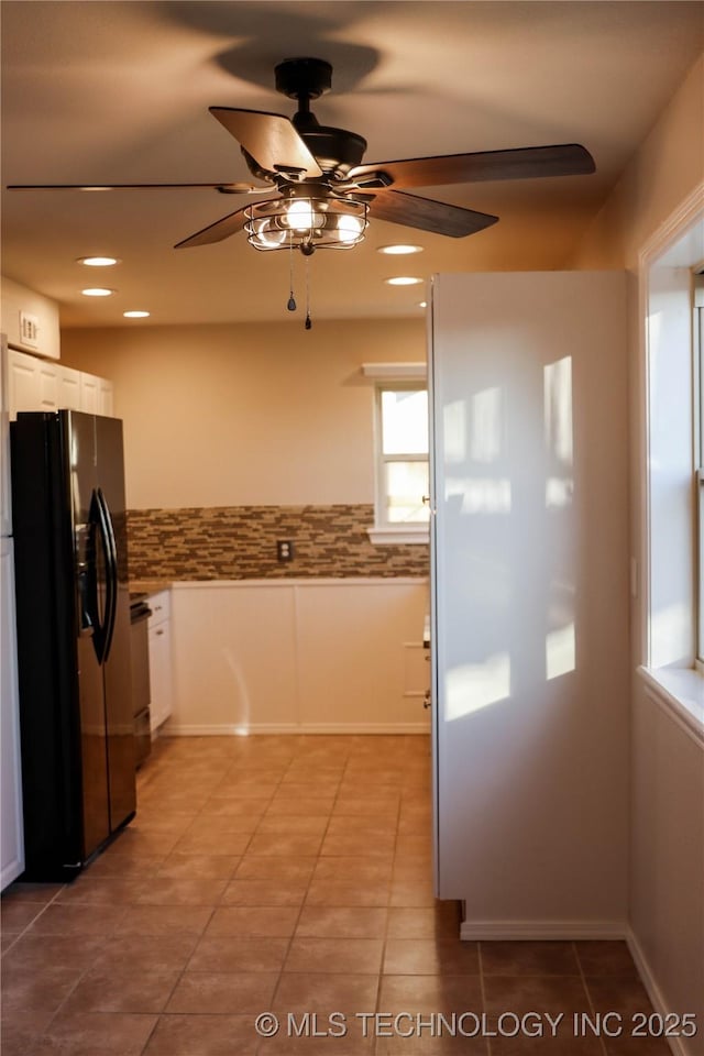 kitchen with dishwasher, white cabinets, light tile patterned flooring, decorative backsplash, and black fridge