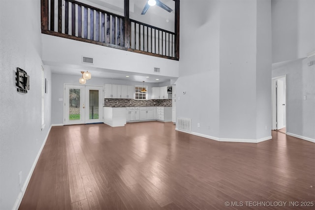 unfurnished living room featuring hardwood / wood-style flooring and a towering ceiling