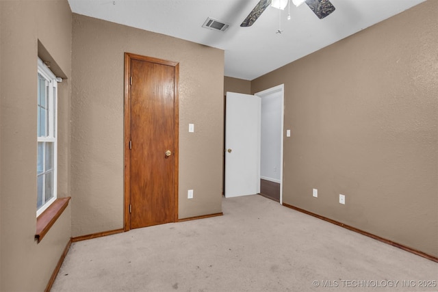 unfurnished bedroom with ceiling fan and light colored carpet