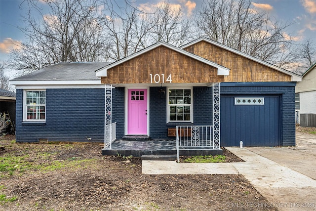 view of front of home with a garage, covered porch, and central AC