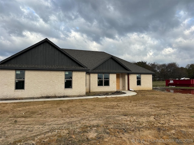 exterior space with brick siding and roof with shingles