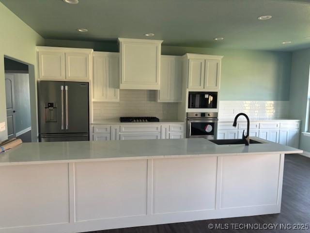 kitchen featuring stainless steel appliances, light countertops, white cabinetry, and a sink