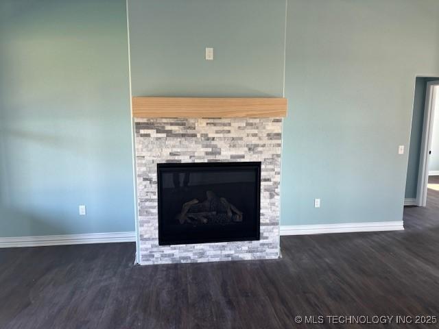 room details featuring baseboards, wood finished floors, and a glass covered fireplace