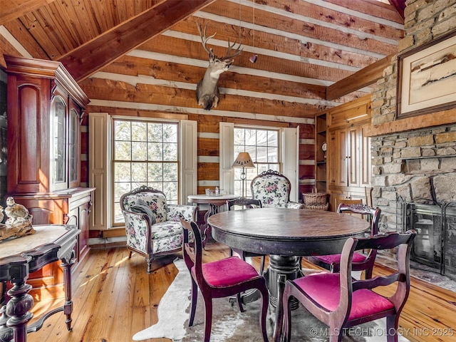 dining space featuring a fireplace, light hardwood / wood-style floors, lofted ceiling with beams, and wooden ceiling