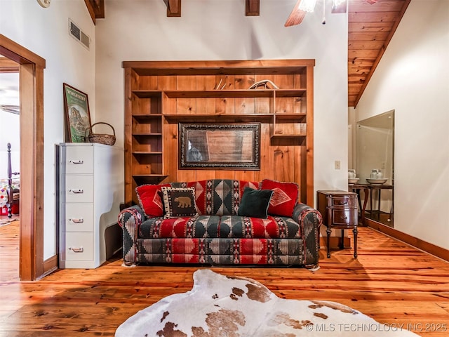 sitting room with ceiling fan, hardwood / wood-style flooring, vaulted ceiling with beams, and wooden ceiling