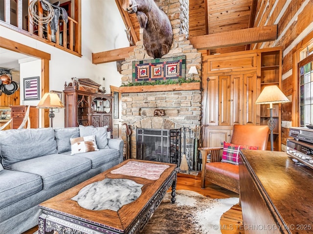 living room with hardwood / wood-style flooring, beam ceiling, a high ceiling, and a fireplace