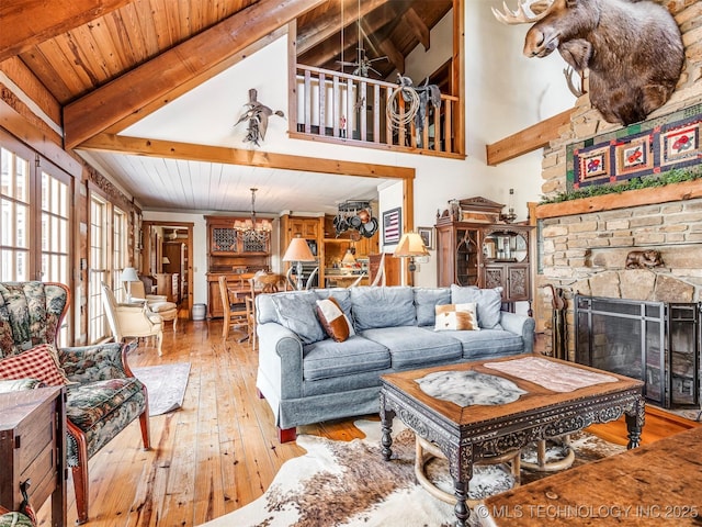 living room with a fireplace, beamed ceiling, a chandelier, and wood-type flooring