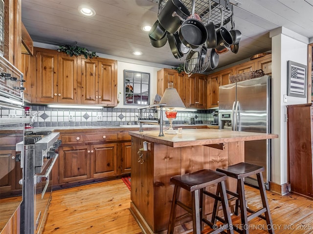 kitchen with wood counters, stainless steel appliances, light hardwood / wood-style flooring, and a kitchen island