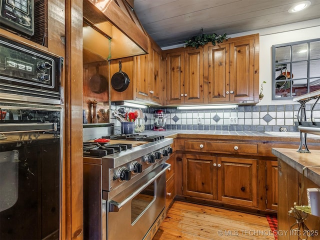 kitchen with light hardwood / wood-style flooring, high end stainless steel range oven, wood ceiling, and decorative backsplash