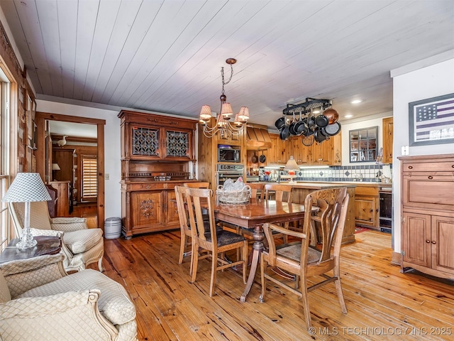 dining room featuring light wood-type flooring, an inviting chandelier, and wood ceiling