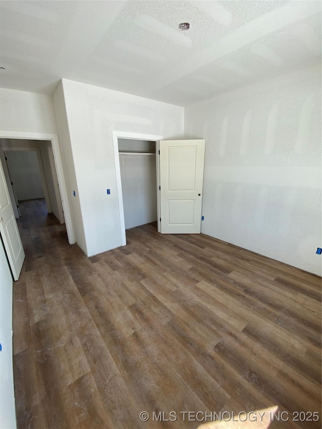 unfurnished bedroom with dark wood-type flooring, a textured ceiling, and a closet