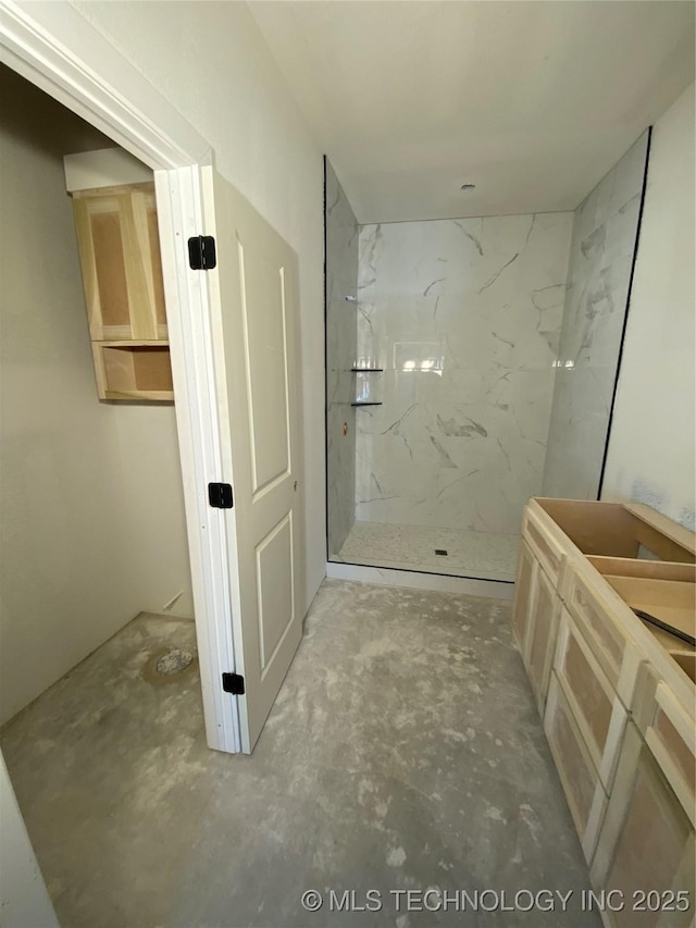 bathroom with a tile shower and concrete flooring