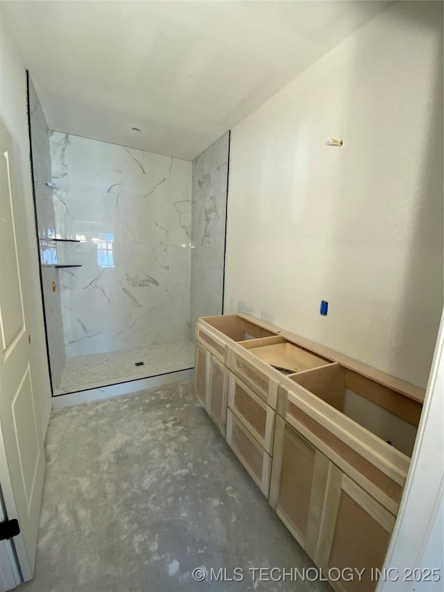 bathroom with a tile shower and concrete floors