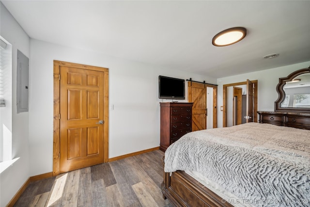 bedroom with light wood-type flooring, electric panel, and a barn door