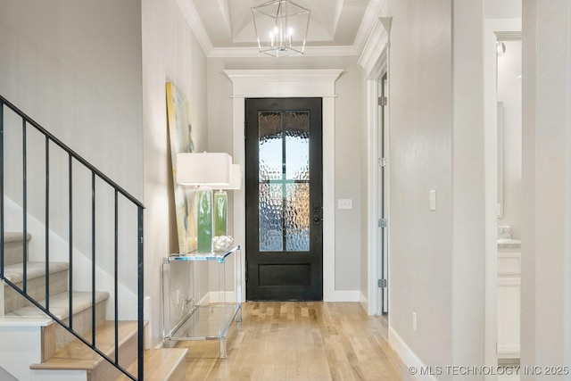 entrance foyer featuring light hardwood / wood-style flooring, crown molding, and an inviting chandelier