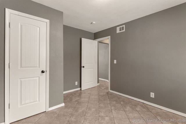 unfurnished bedroom featuring baseboards, visible vents, and light tile patterned flooring