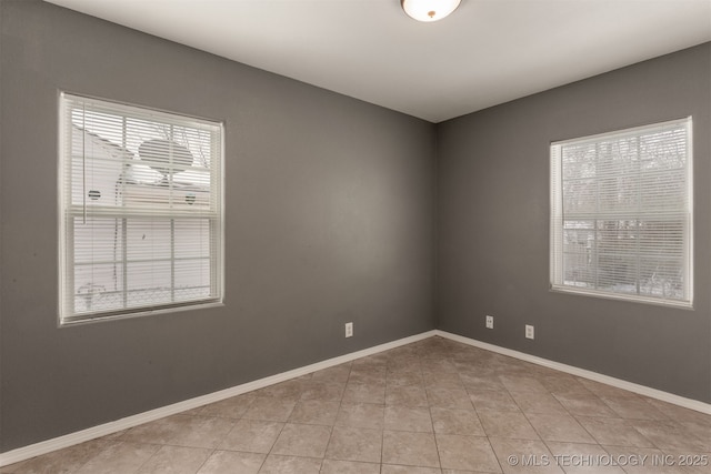 spare room featuring light tile patterned flooring and baseboards