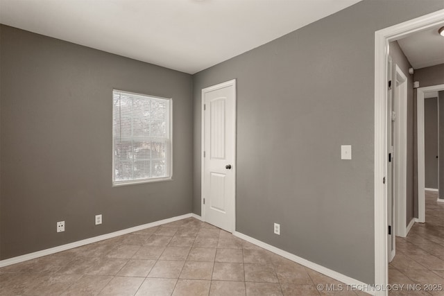 empty room with light tile patterned floors and baseboards