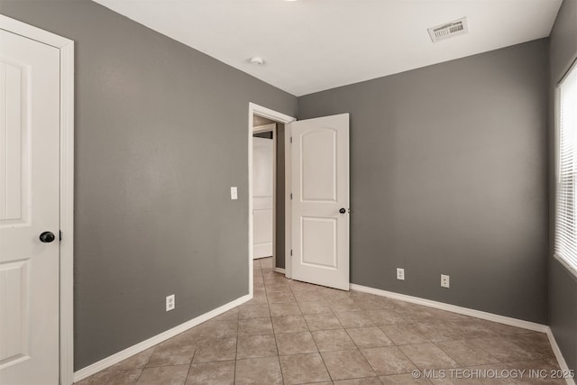 unfurnished bedroom with light tile patterned flooring, visible vents, and baseboards