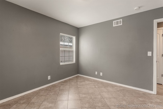 spare room featuring light tile patterned floors, baseboards, and visible vents