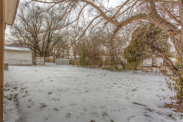 snowy yard featuring a detached garage and central AC unit