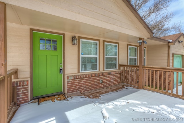 snow covered property entrance with brick siding