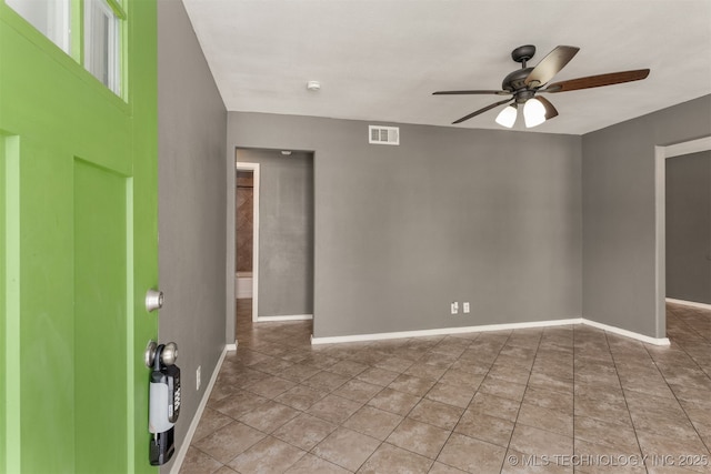 tiled spare room with ceiling fan, visible vents, and baseboards