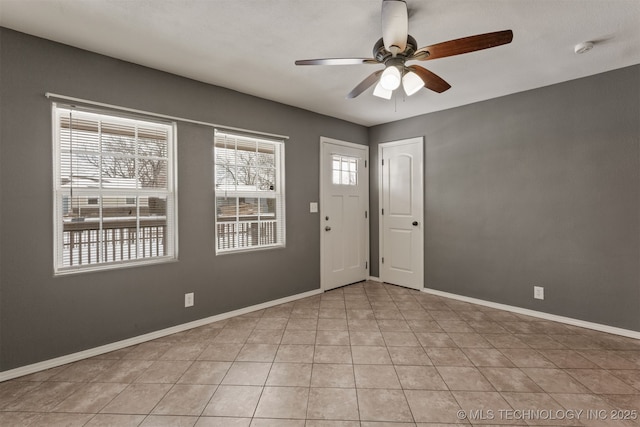 unfurnished room featuring light tile patterned floors, a ceiling fan, and baseboards