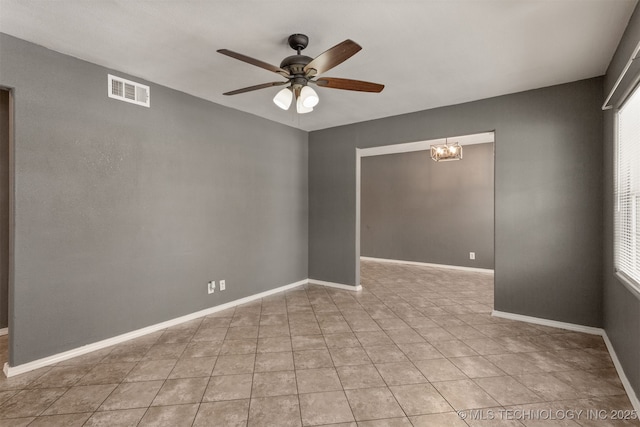 spare room with light tile patterned flooring, visible vents, baseboards, and ceiling fan with notable chandelier