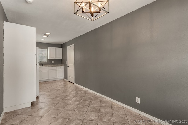 unfurnished dining area featuring light tile patterned floors, a notable chandelier, baseboards, and a sink