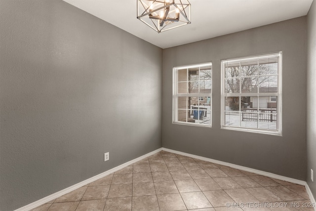 unfurnished room with light tile patterned flooring, a notable chandelier, and baseboards